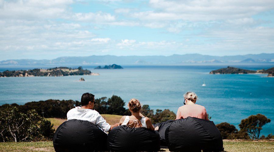 Two women are sitting at a table with a view of the ocean from Mudbrick Winery