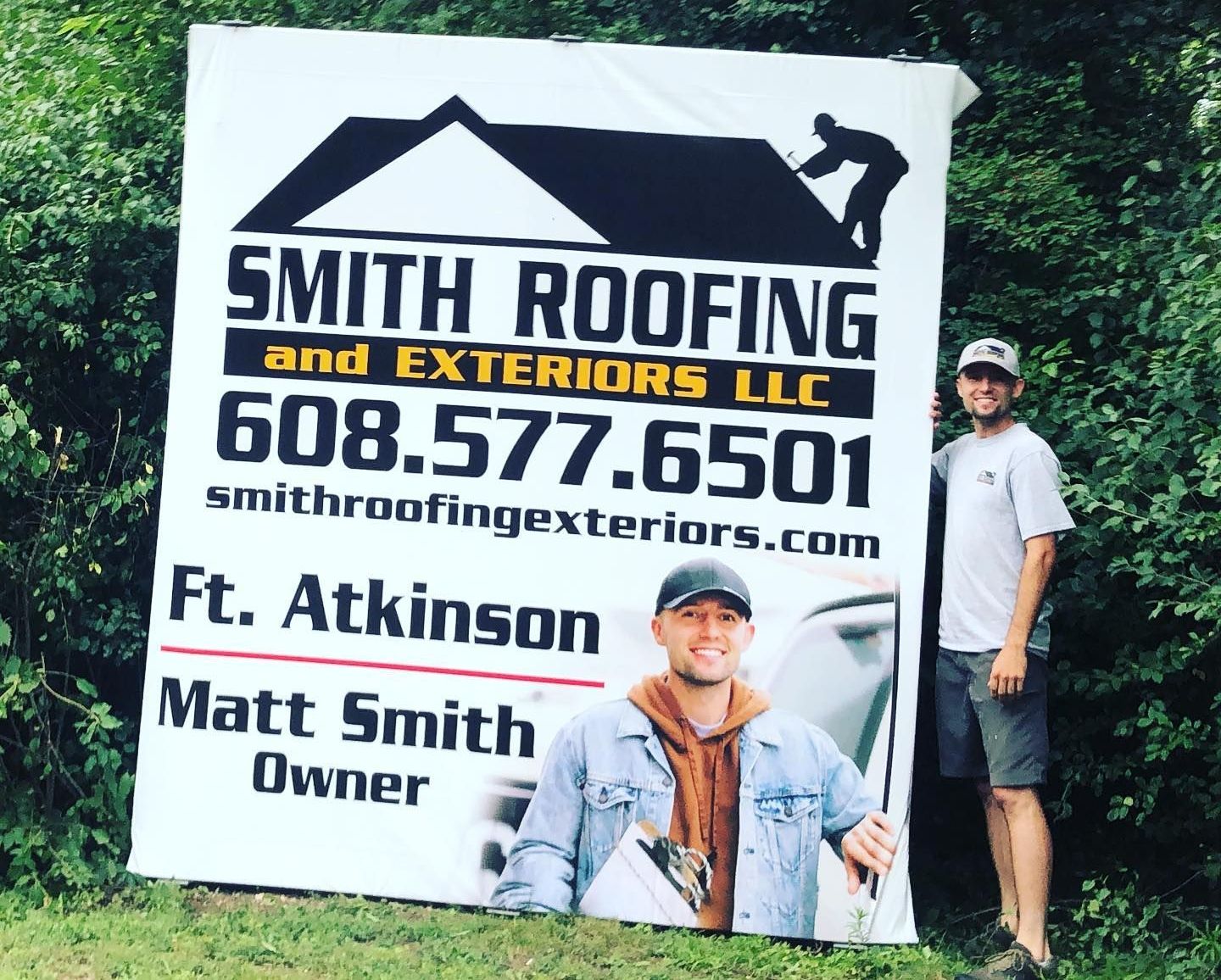 a man holding a sign for smith roofing and exteriors llc