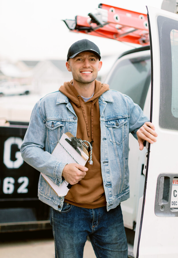 picture of business owner in a denim jacket holds a clipboard in front of a truck