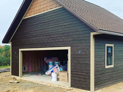 a large black garage with a brown roof is being built .