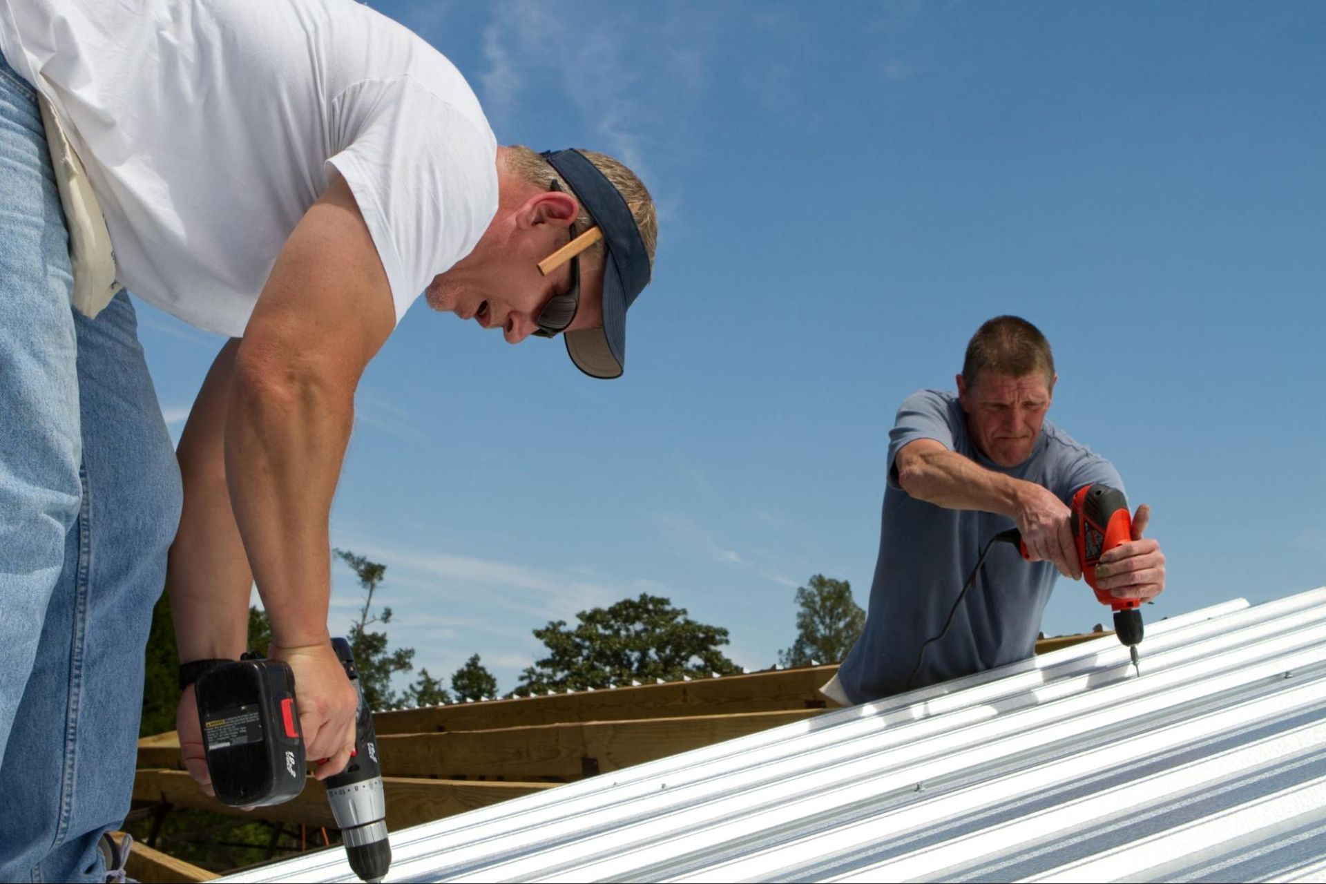 Two men are working on a metal roof.