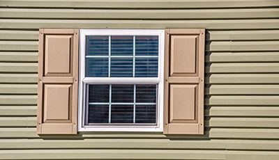 A window with shutters on the side of a house.