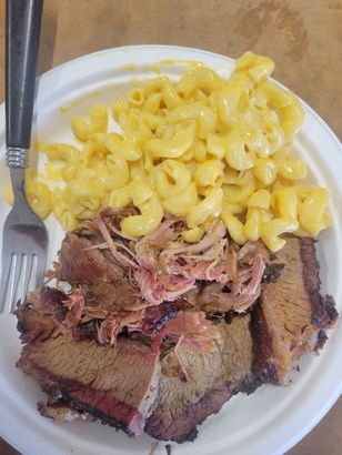 Brisket and pulled pork with mac and cheese on a white plate, served with a fork.