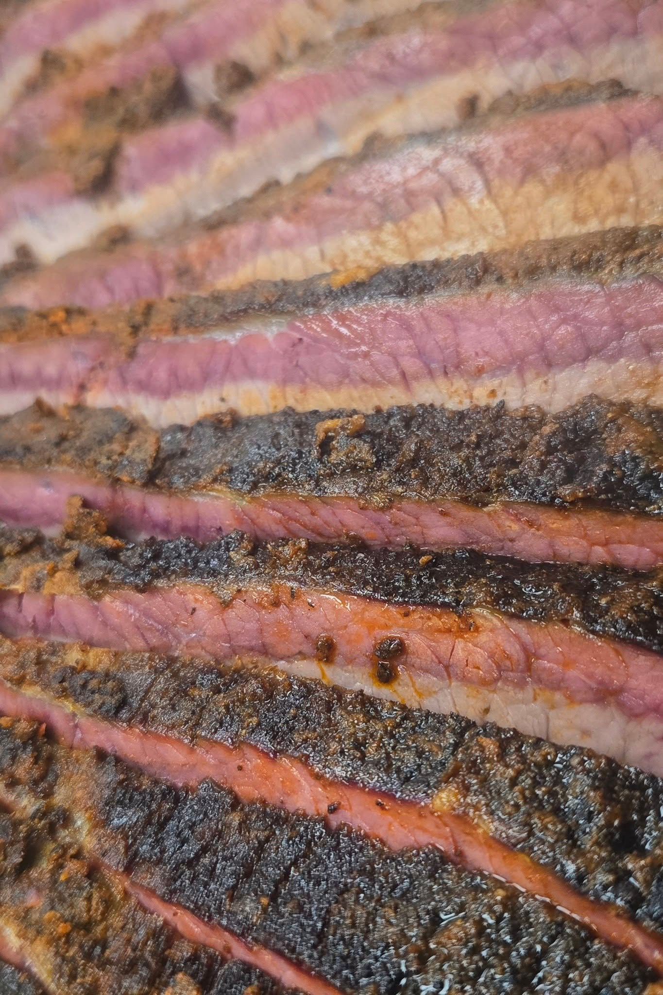 Sliced smoked brisket with a pink smoke ring and black bark.