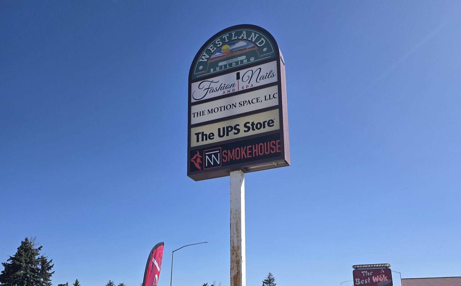 Sign for Westland Shopping Center with tenant names, on a sunny day.