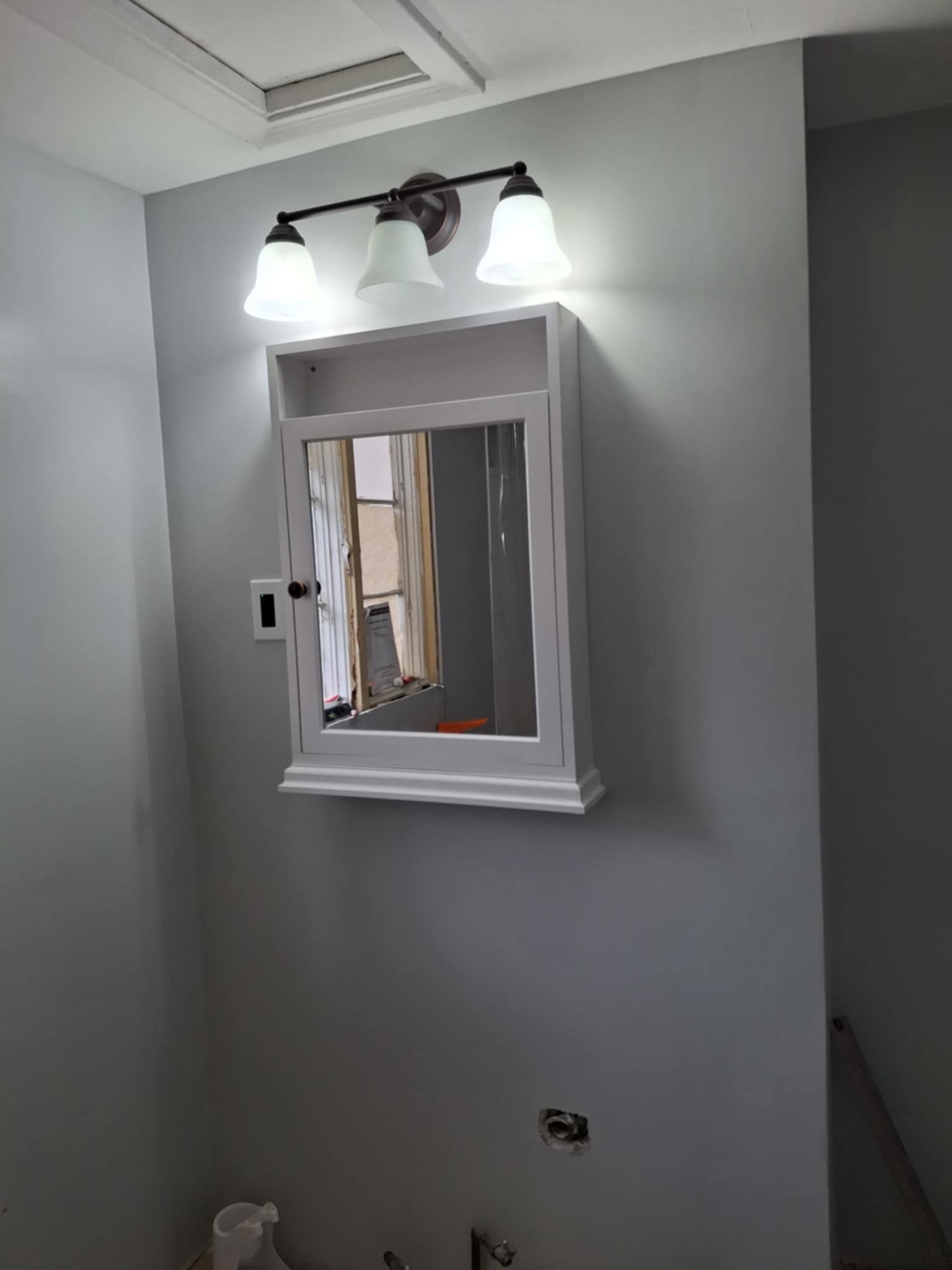 A bathroom with a medicine cabinet and a mirror.