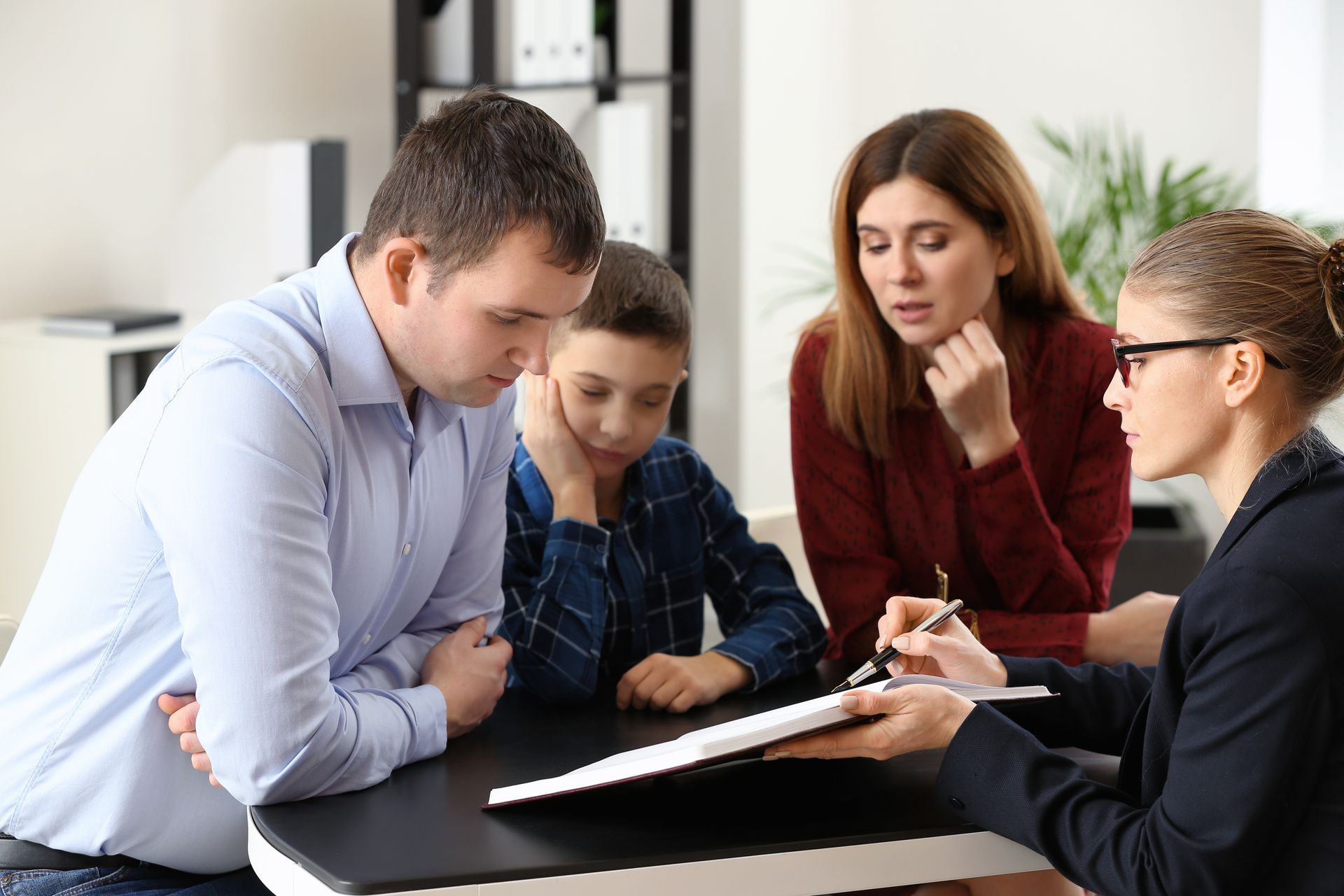 Family and counselor review documents at a desk in an office.