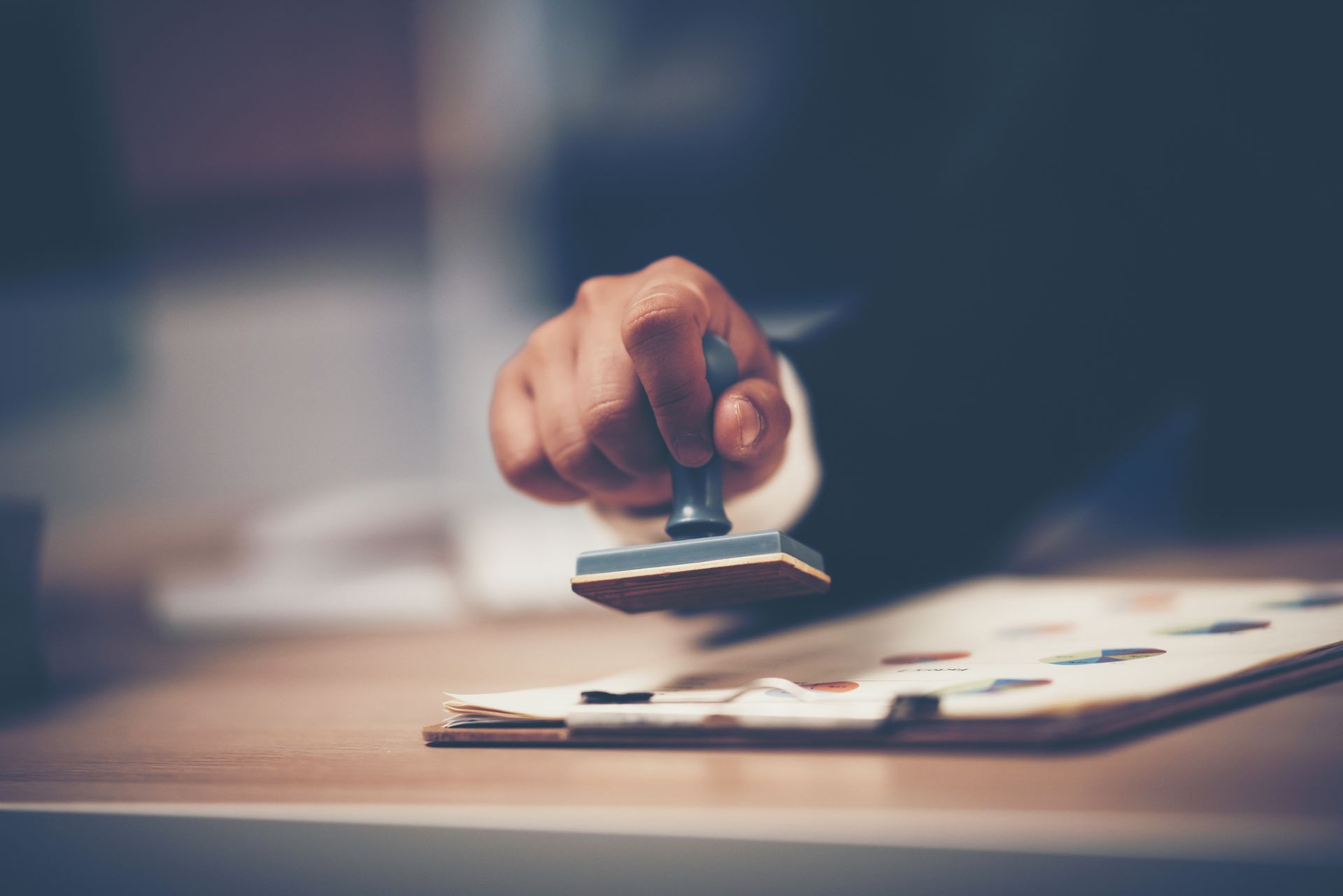 Hand holding a stamp, about to press it on a document.