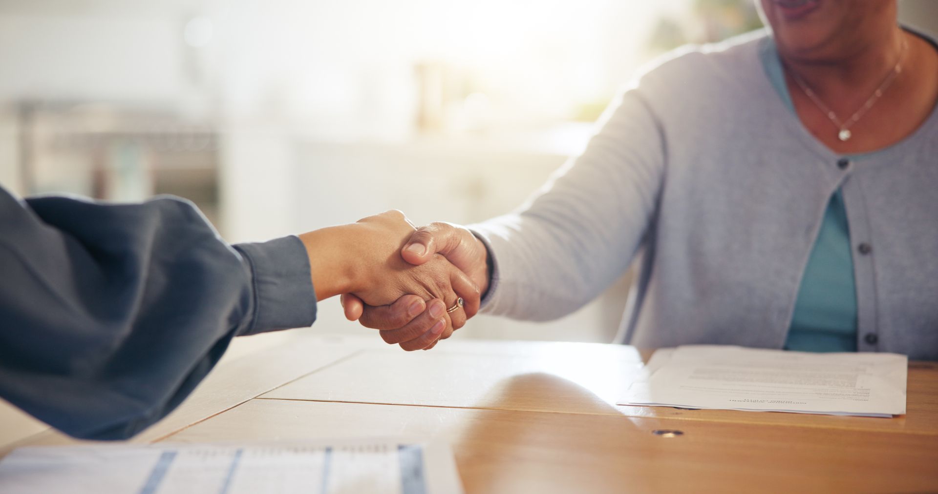 Two people shaking hands over a table.