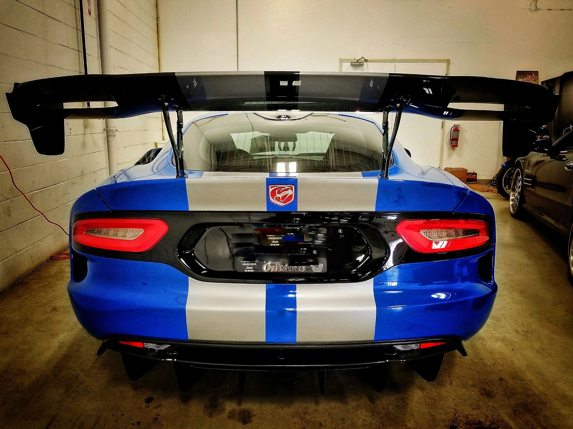 Blue and silver Dodge Viper with large rear wing in a garage.