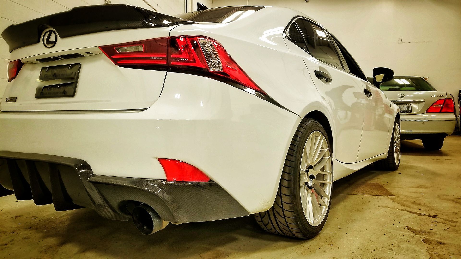White Lexus sedan with a black spoiler and aftermarket rear diffuser.