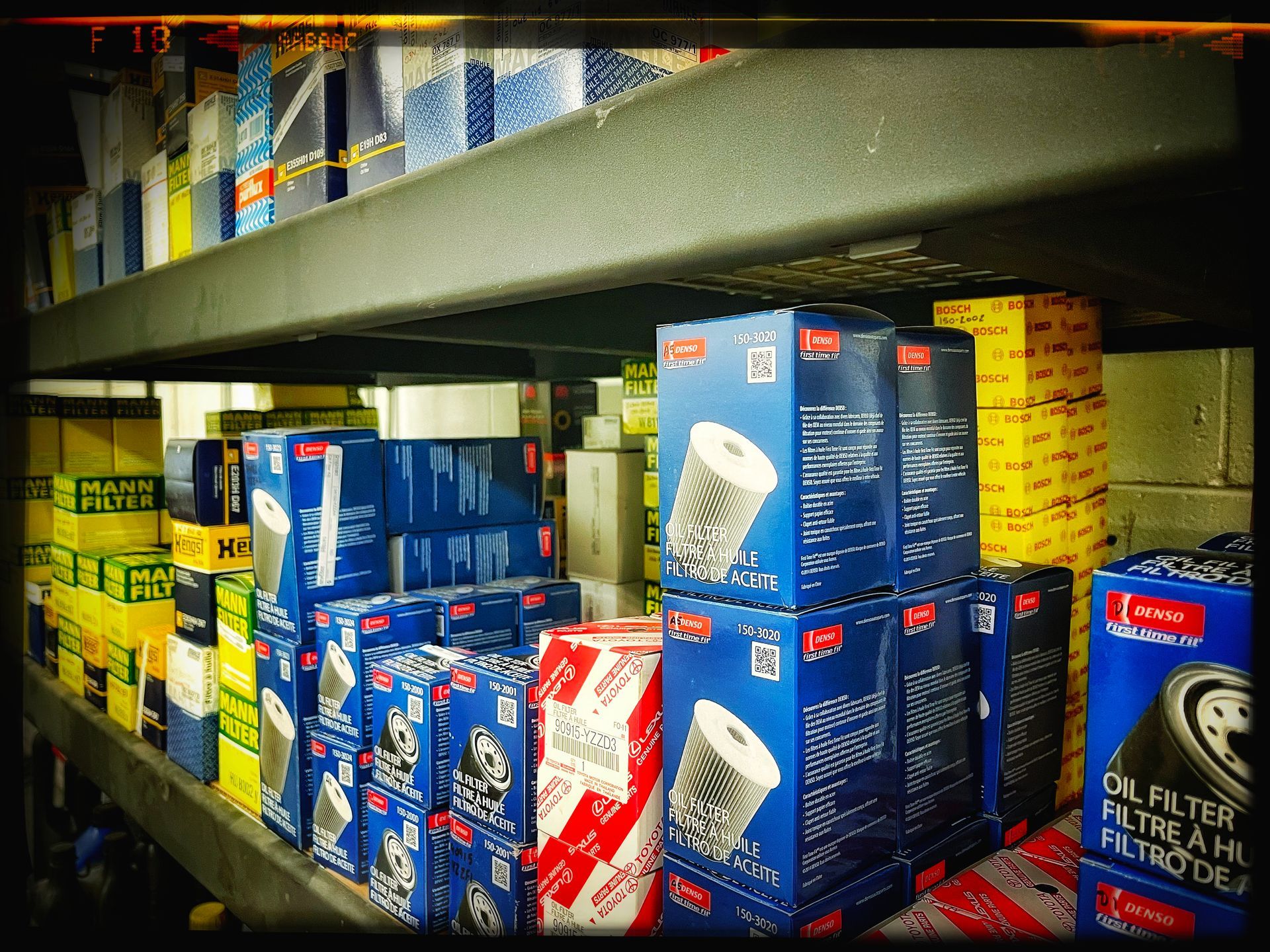Shelves stocked with various automotive oil filters in boxes of blue, yellow, red, and white. | Mecano Autoworks