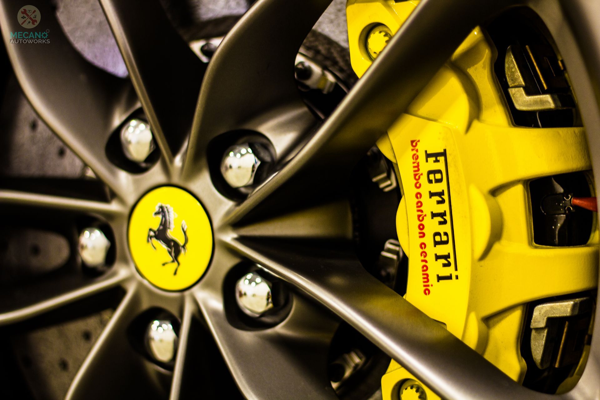 Close-up of a Ferrari wheel with a yellow brake caliper, featuring the Ferrari logo. | Mecano Autoworks