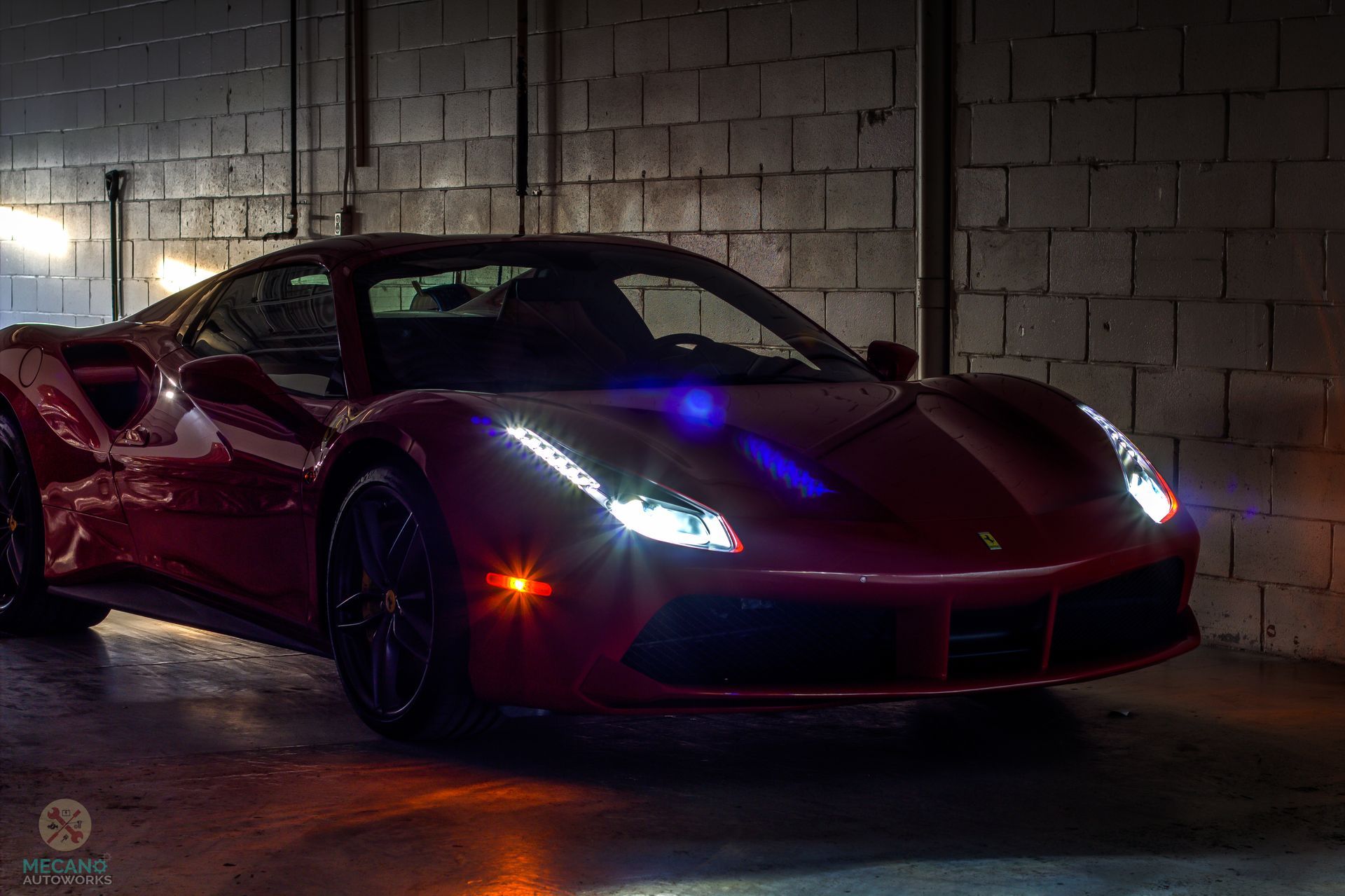 Red Ferrari sports car parked in a dimly lit garage with brick walls. | Mecano Autoworks
