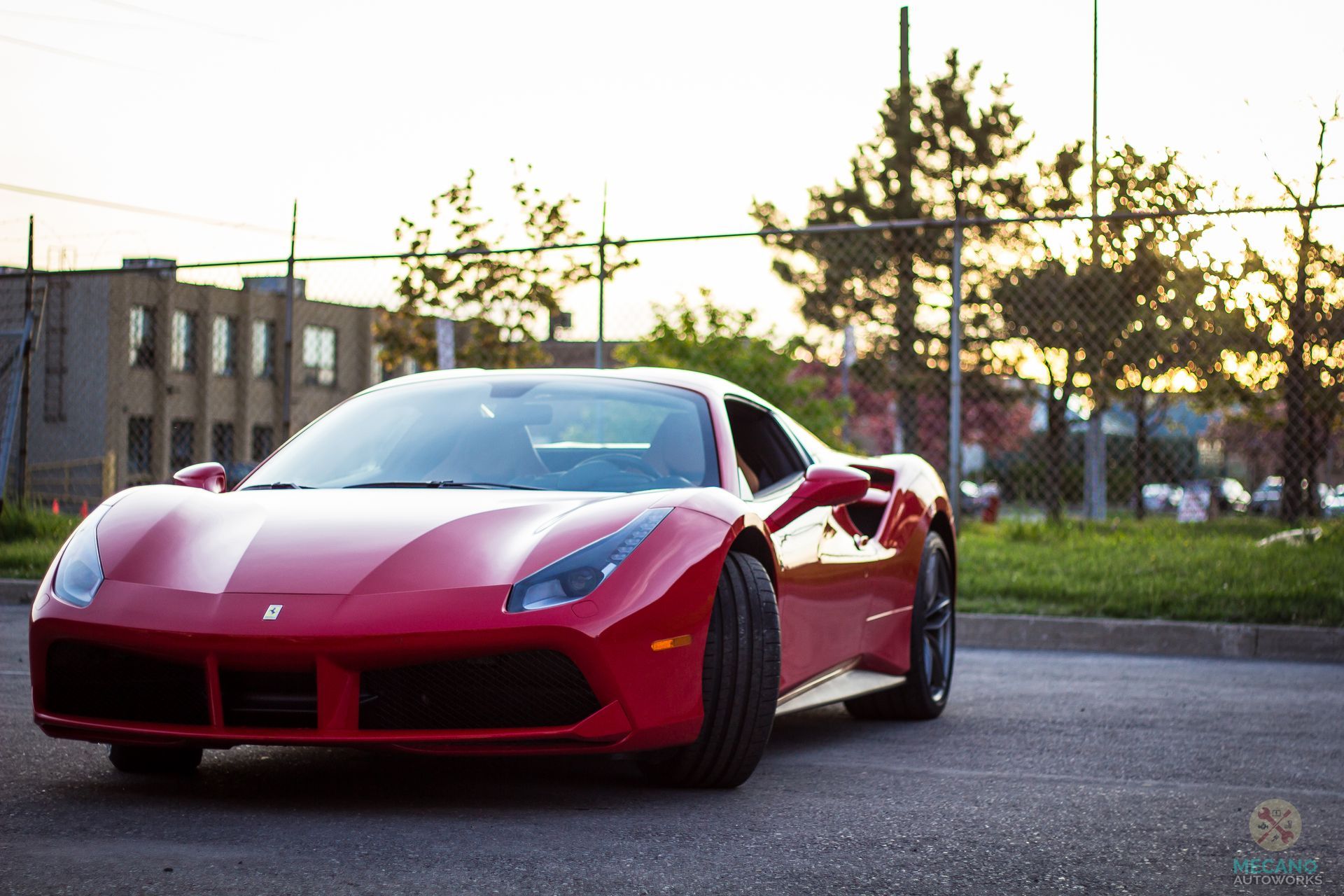 Red Ferrari sports car parked on asphalt with a sunset in the background. | Mecano Autoworks