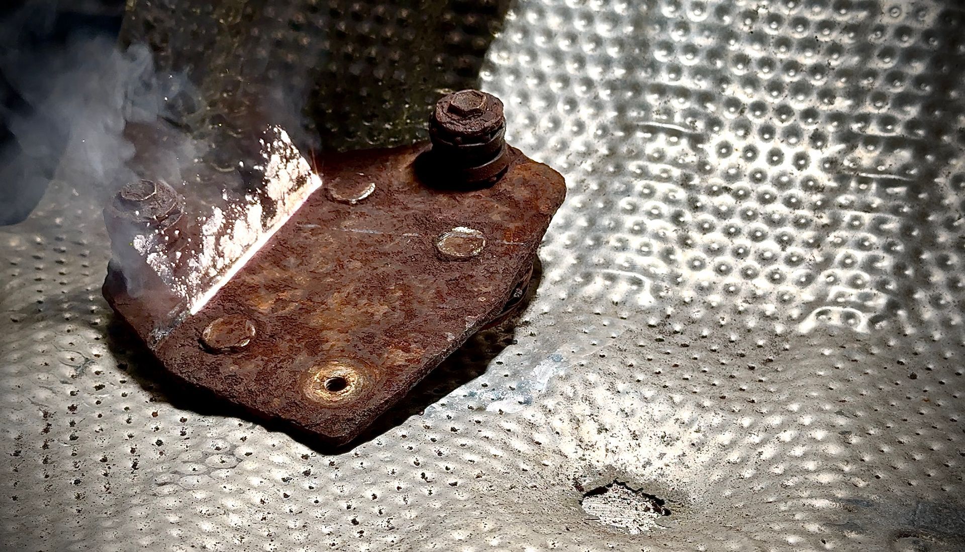 A rusted metal bracket being treated with a pulsed lazer rust removal machine