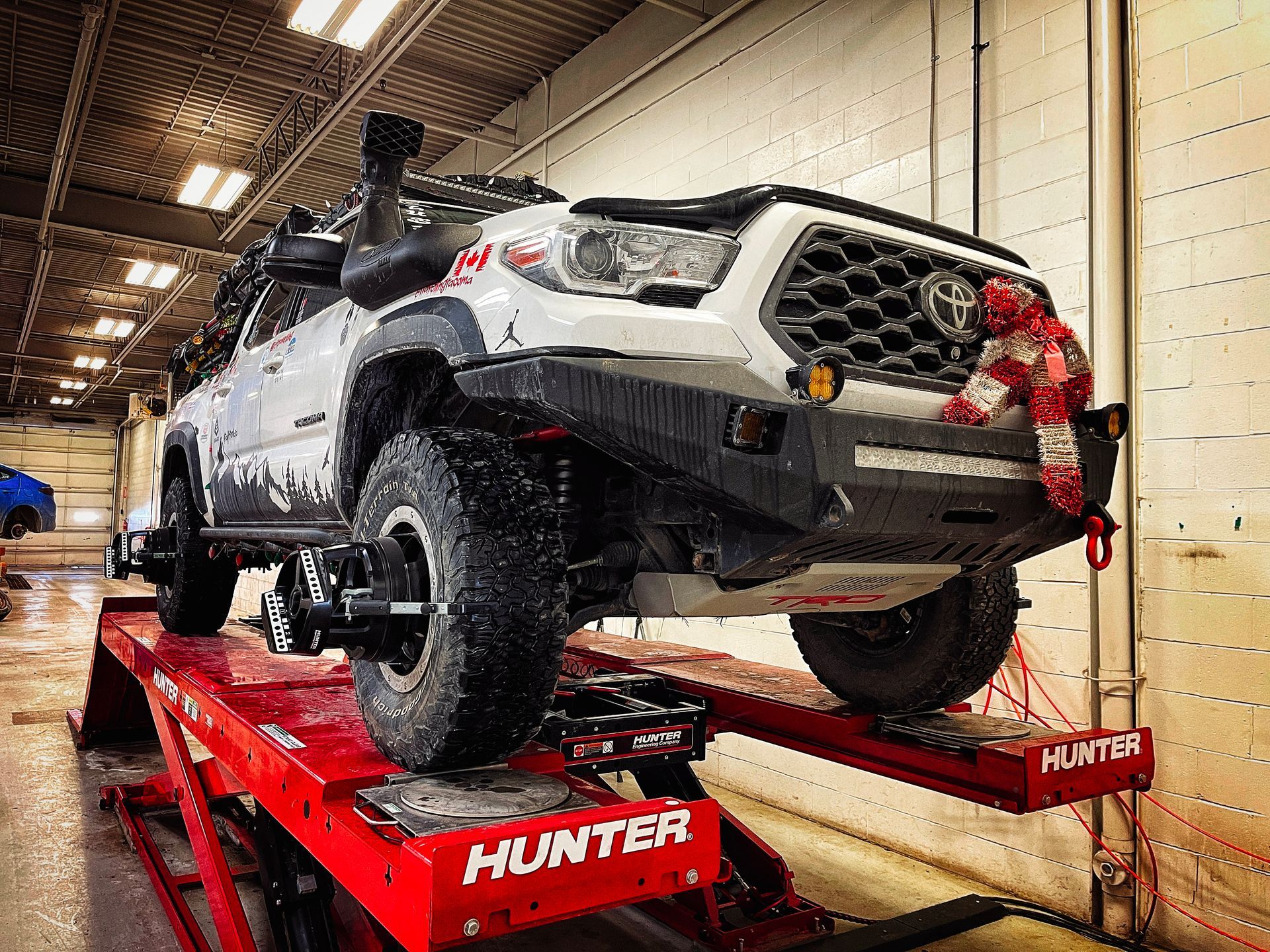 White off-road Toyota Tacoma on a red Hunter lift, black fender flares, and a snorkel. | Mecano Autoworks