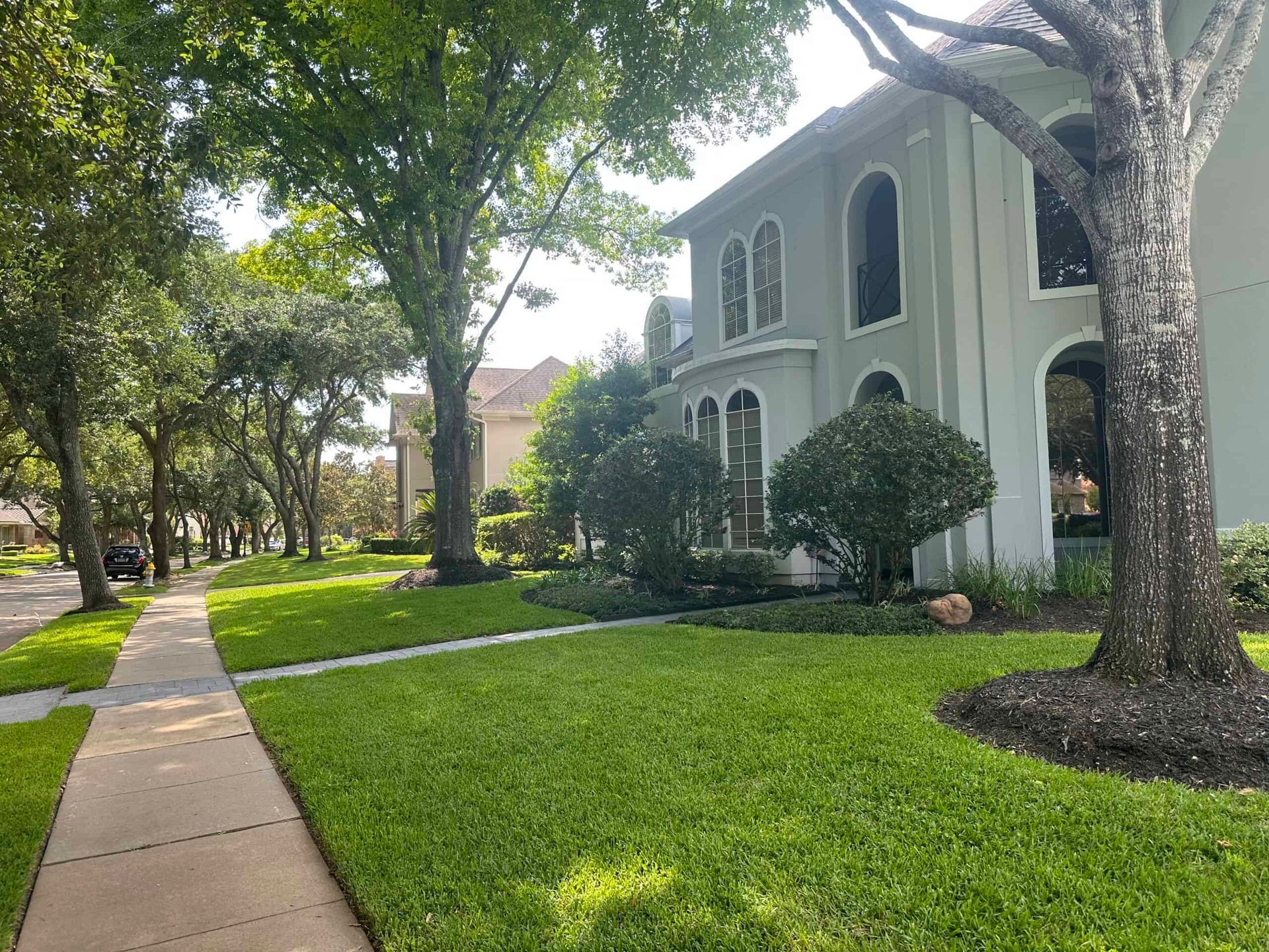 A large house with a lush green lawn and trees in front of it.