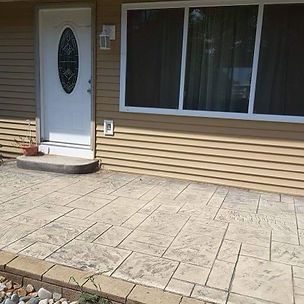 A house with a concrete patio in front of it and a white door.