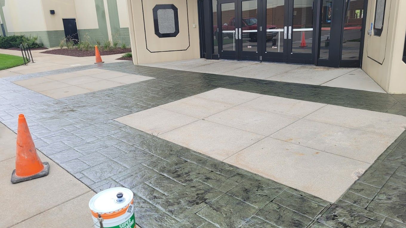 A bucket of paint is sitting on the sidewalk in front of a building.