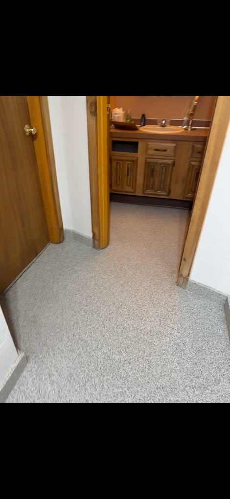 A hallway leading to a kitchen with a sink and cabinets.
