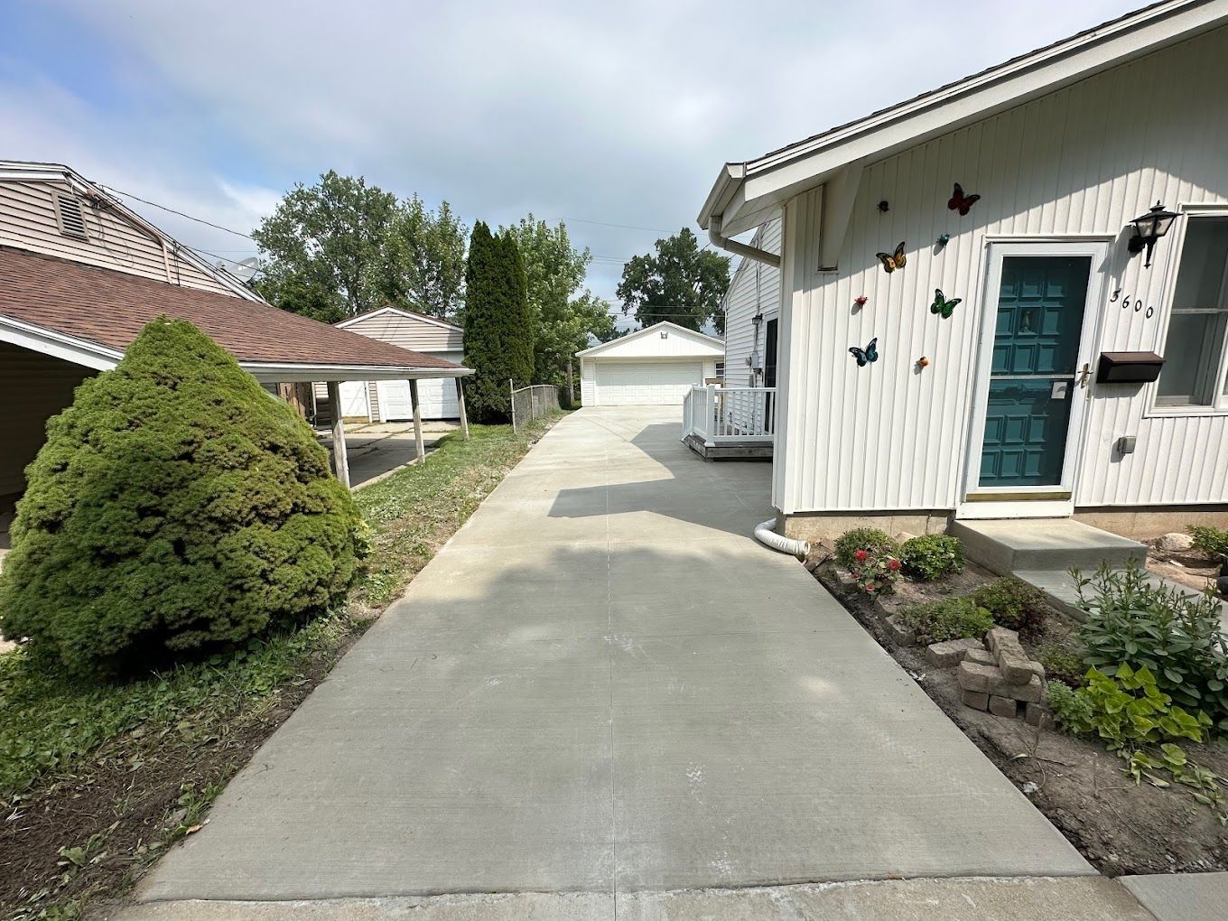 A driveway leading to a white house with a blue door
