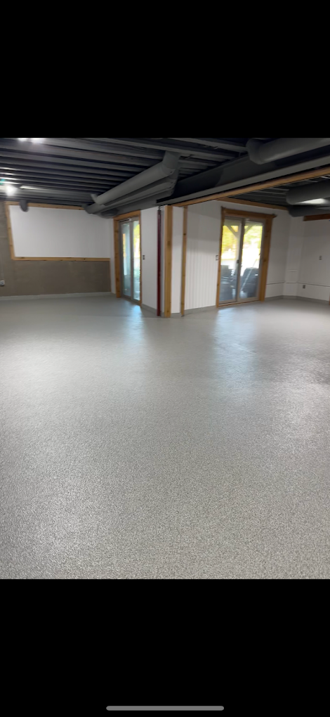 A large empty room with a concrete floor and sliding glass doors.