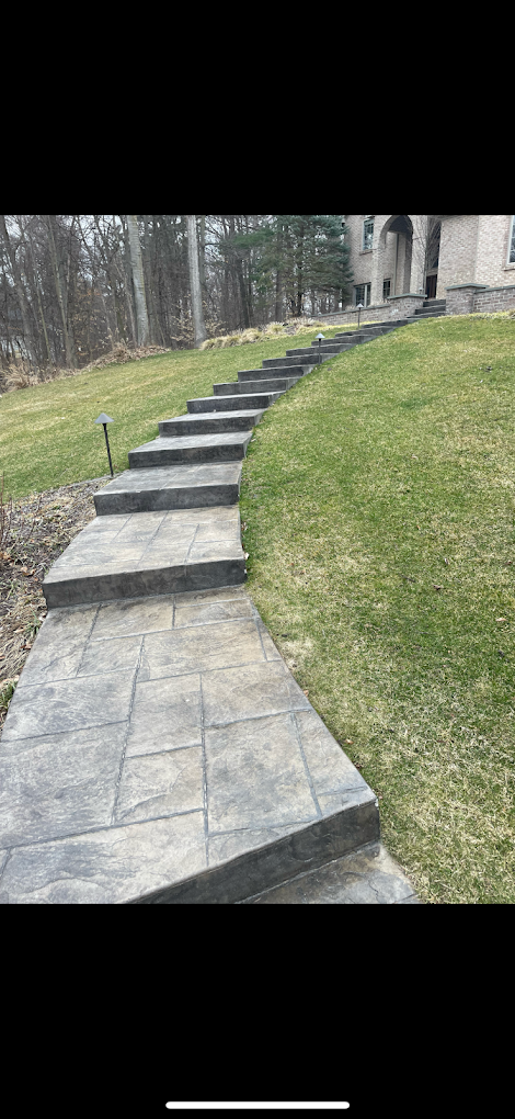 A concrete walkway with steps leading up to a house.