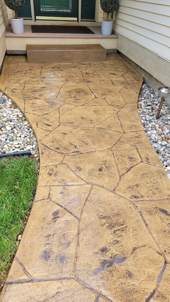 A concrete walkway leading to the front door of a house.
