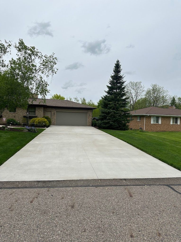 A concrete driveway leading to a house with a garage.