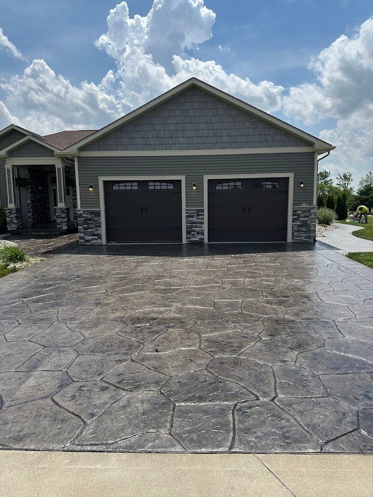 A house with two garage doors and a concrete driveway in front of it.