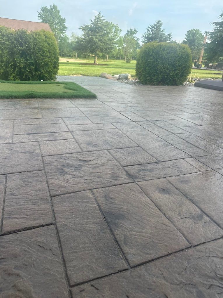 A concrete patio with trees in the background and a house in the background.