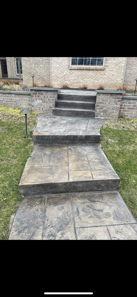 A concrete walkway with stairs leading up to a house.