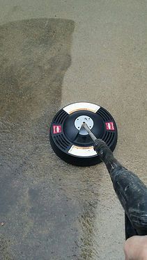 A person is using a pressure washer to clean a concrete floor.