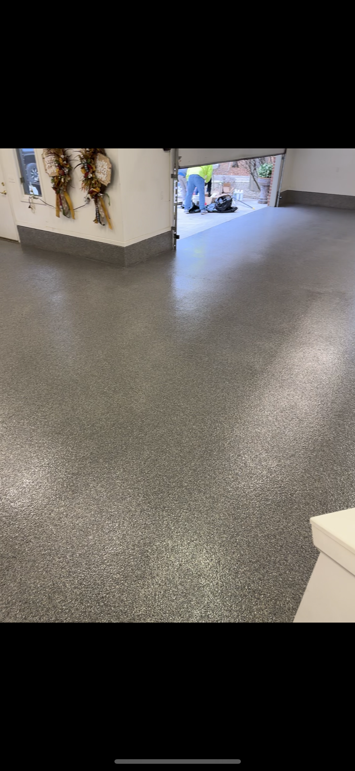 A garage with a gray floor and a white wall.