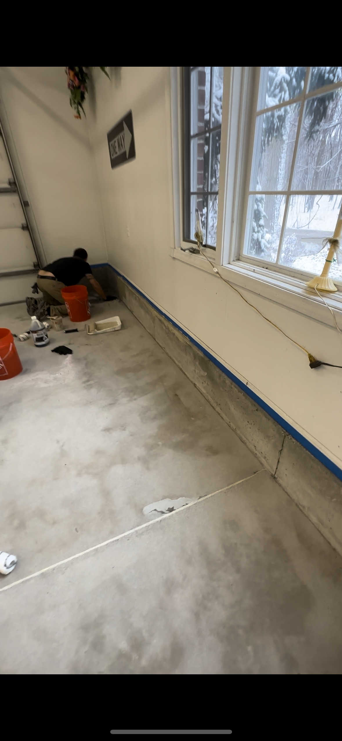 A garage with a window and a bucket on the floor.