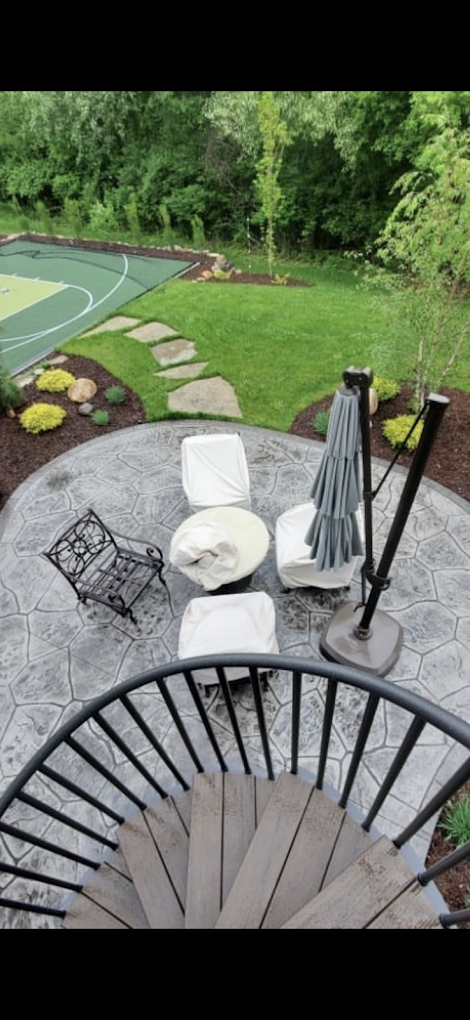 A spiral staircase leading up to a patio with chairs and umbrellas.