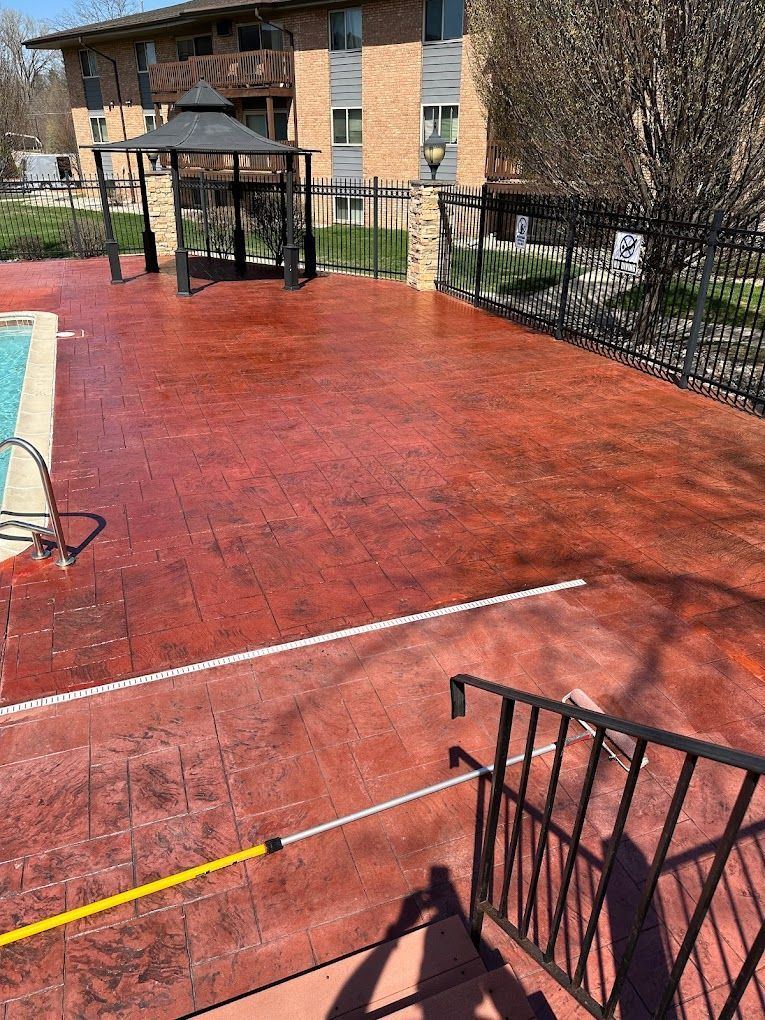 A red concrete deck next to a swimming pool.