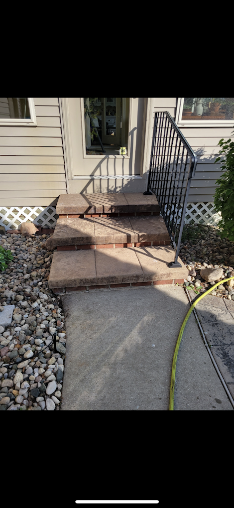 A set of stairs leading up to a house with a metal railing.