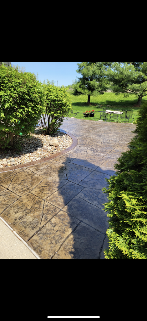 A concrete patio with a bench and trees in the background.