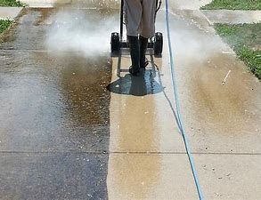 A person is using a pressure washer to clean a sidewalk.