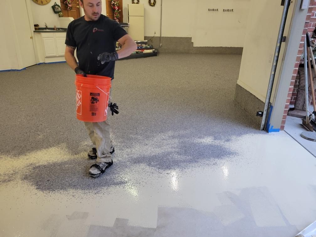 A man is standing in a garage holding an orange bucket.