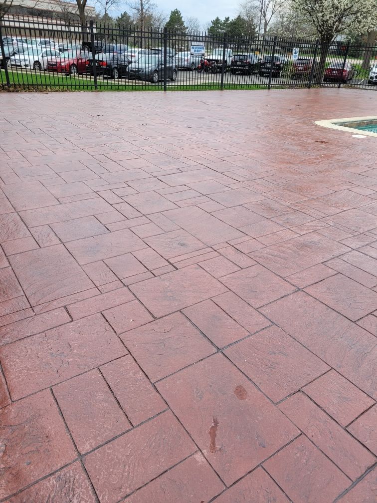A brick driveway with a pool in the background