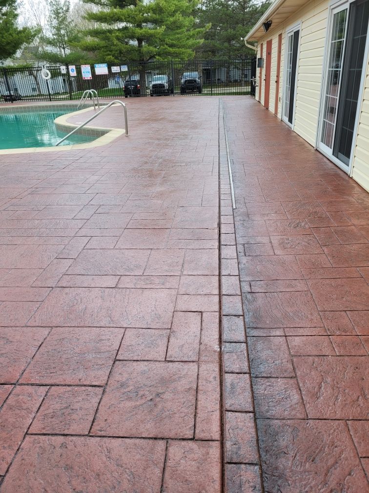 A patio with a pool in the background and a house in the background.