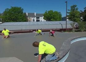 A group of people are working on a concrete surface.