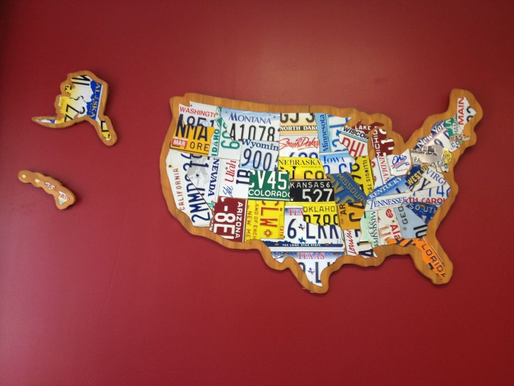 Map of the United States made from license plates, wooden border, mounted on a red wall.