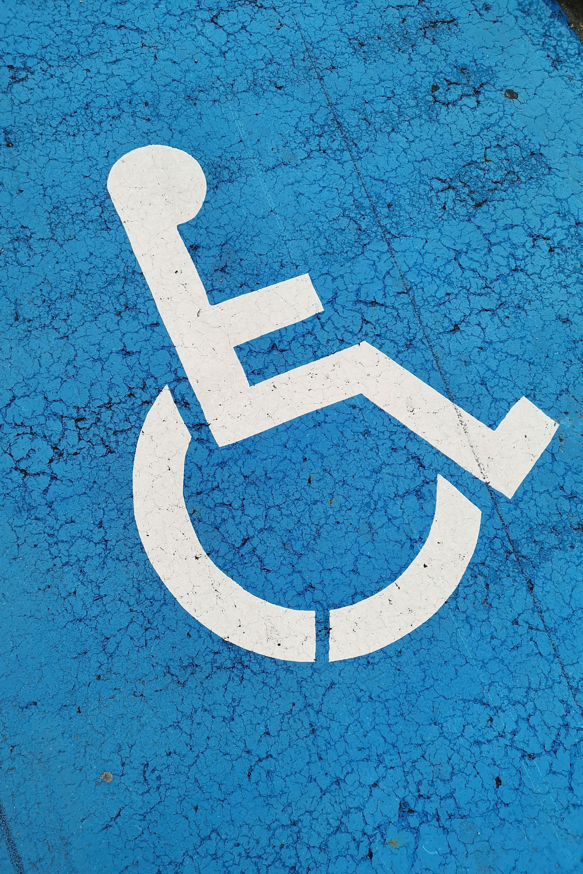 White wheelchair symbol painted on blue pavement.