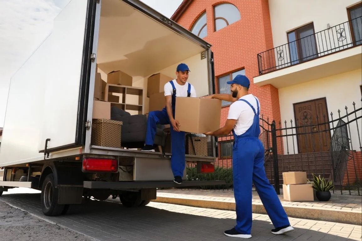 Movers loading furniture and boxes into a large white moving truck.