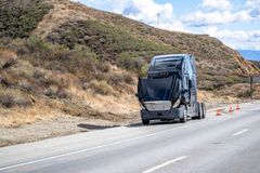 A semi truck is driving down a highway next to a mountain.