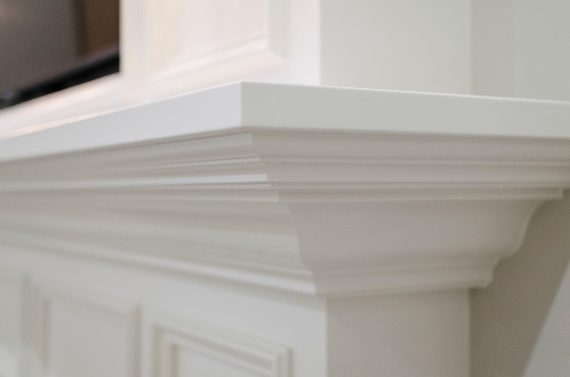 White fireplace mantel with layered molding and flat top.
